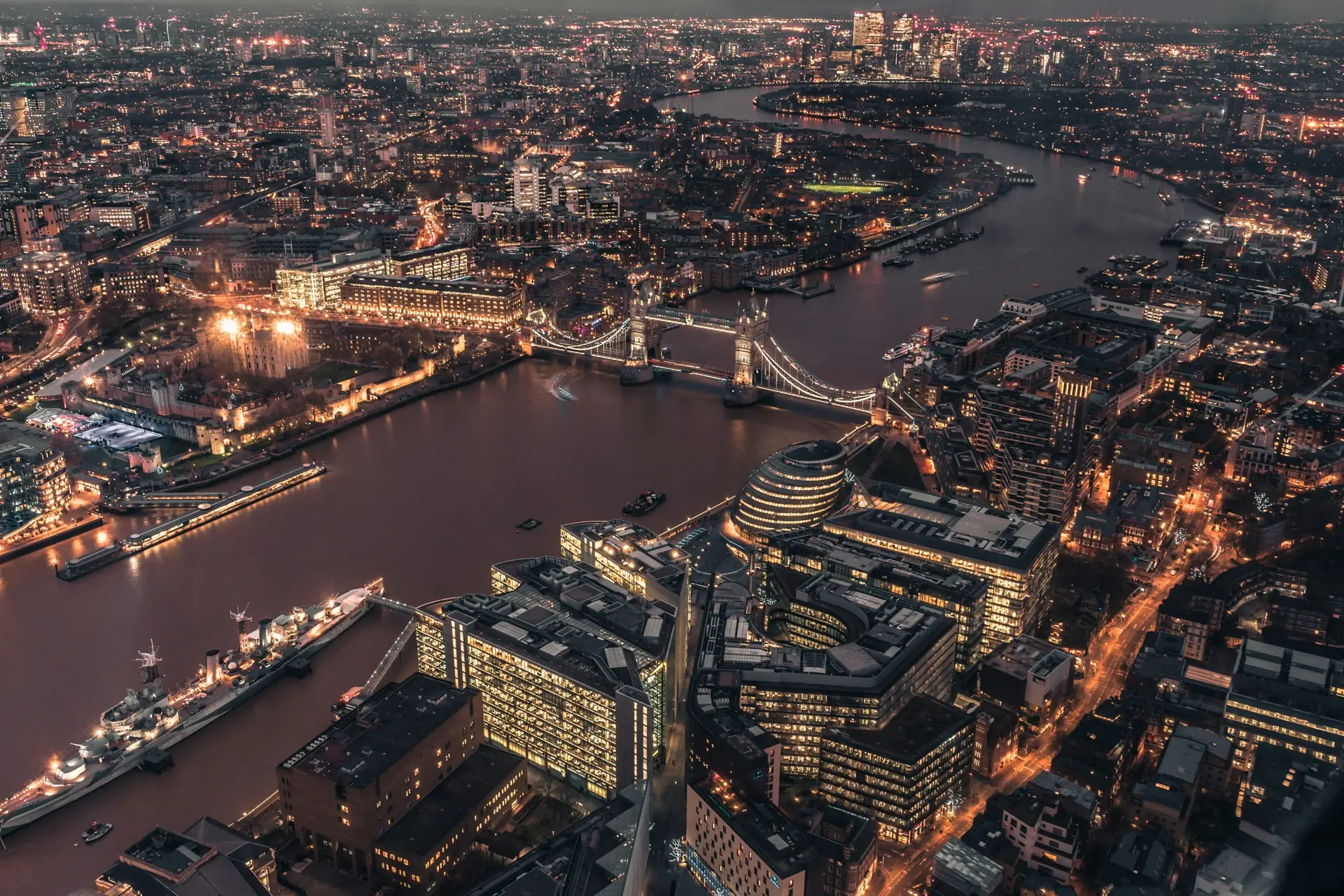Aerial photograph of London at night, Tower Bridge lit up over the Thames with Canary Wharf on the horizon — Stagg Studio, web design in South East London.
